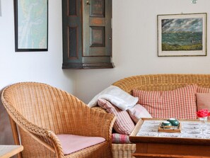 A wicker chair, a sofa with checkered cushions, a framed painting, and a door with a keyhole. - Karoline House Apartment Lise (Utersum)