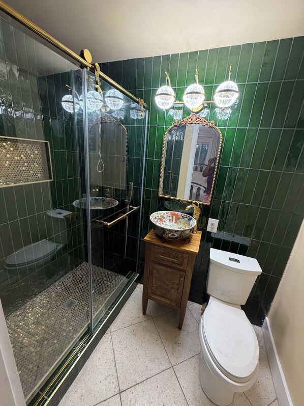 A bathroom with a glass-enclosed shower, a toilet, and a sink with a decorative bowl. - La Belle Maison in charming Macon with large fenced in yard (Macon)