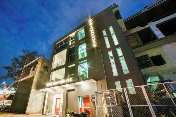 A multi-story building with a prominent 'EXOTOWNHOUSE' sign, large windows, and a gated entrance.
