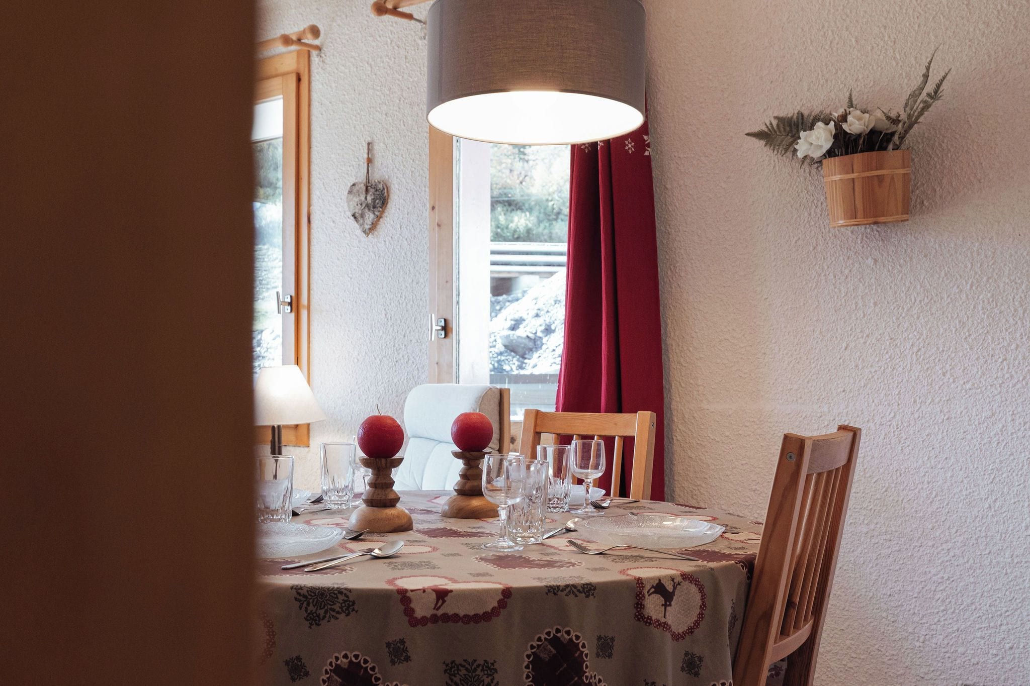 A dining table set with plates, glasses, and a red fruit centerpiece.