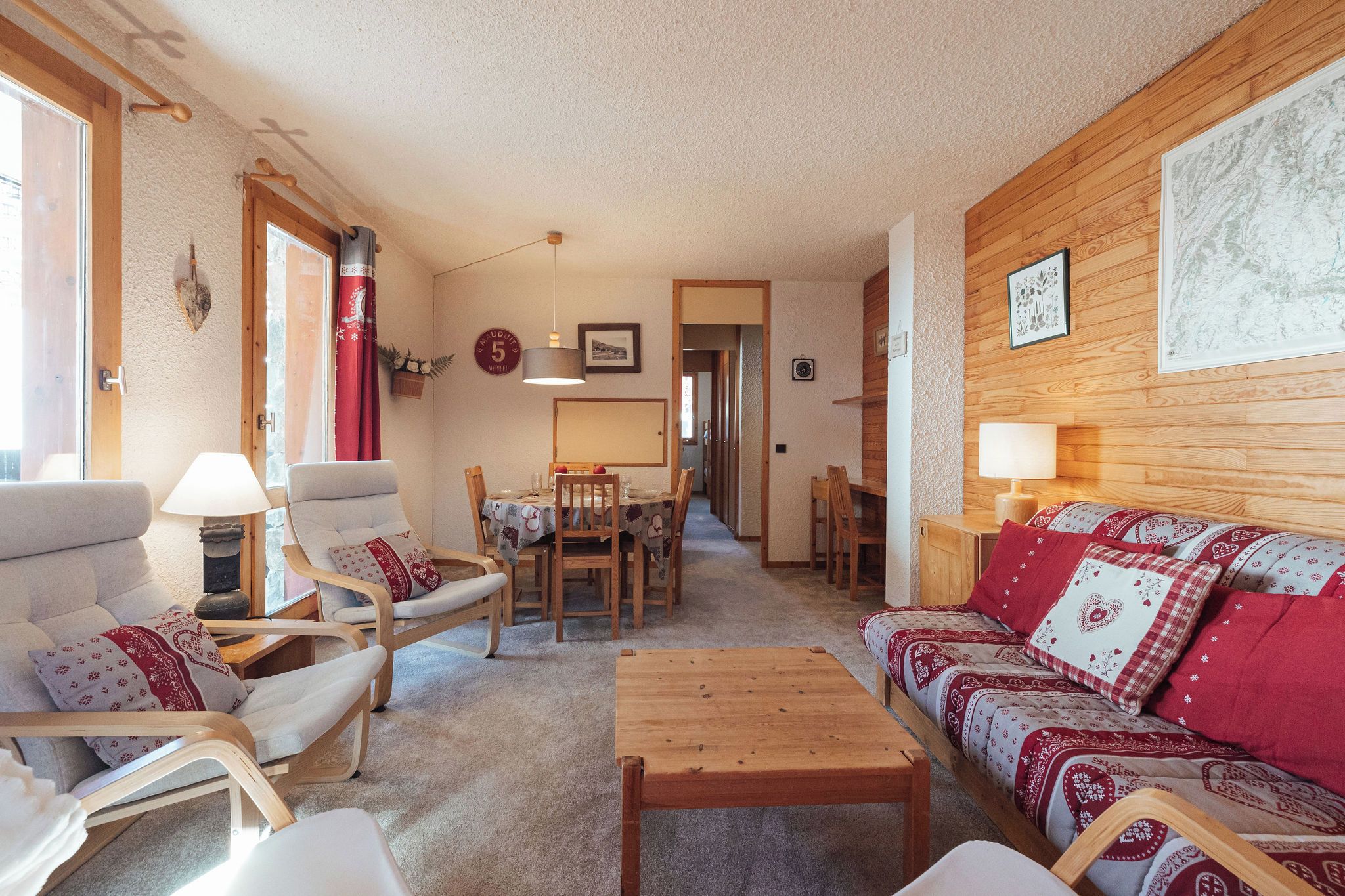 A cozy living room with a sofa, chairs, a dining table, and a wooden coffee table.