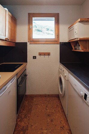 A compact kitchen with a window, a washing machine, and a stove. - Les Verdons (Les Allues)