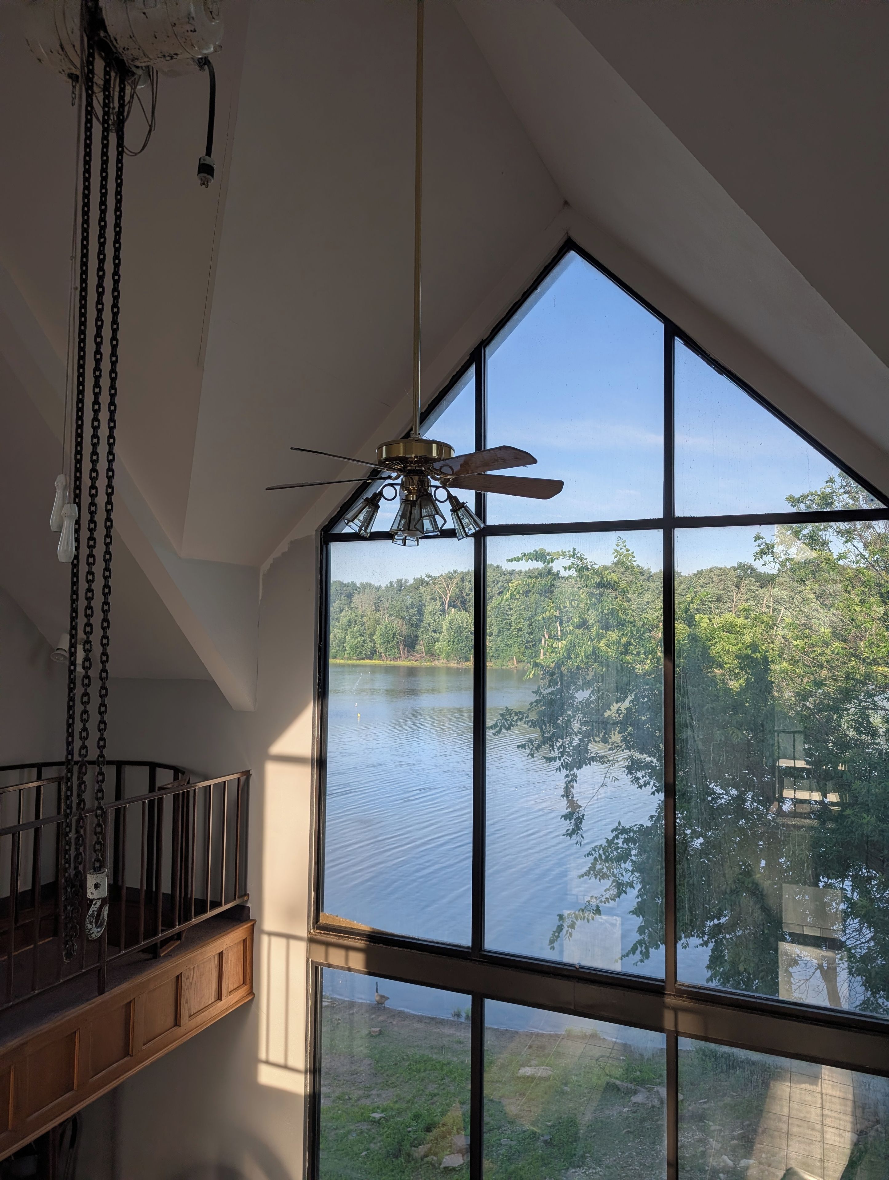 Ein Zimmer mit großem Fenster und Blick auf einen See und Bäume.