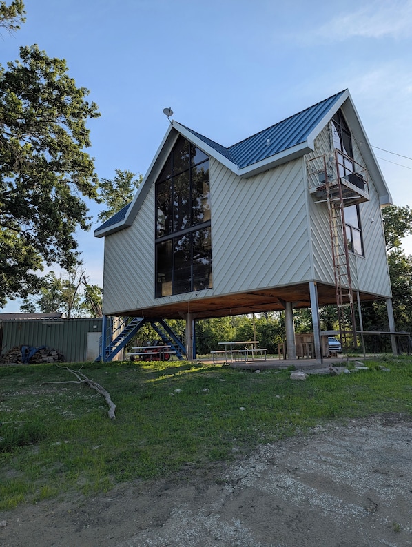 A two-story house with a sloped roof, large windows, and a covered porch area.