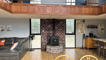 A living room with a fireplace, a sofa, a dining area, and a kitchen.