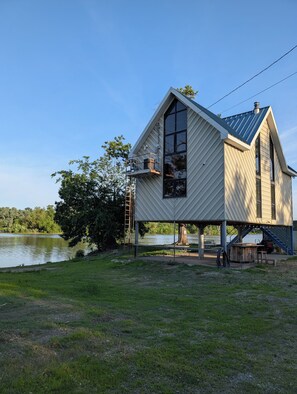 A house with a large window, a balcony, and a view of a lake.