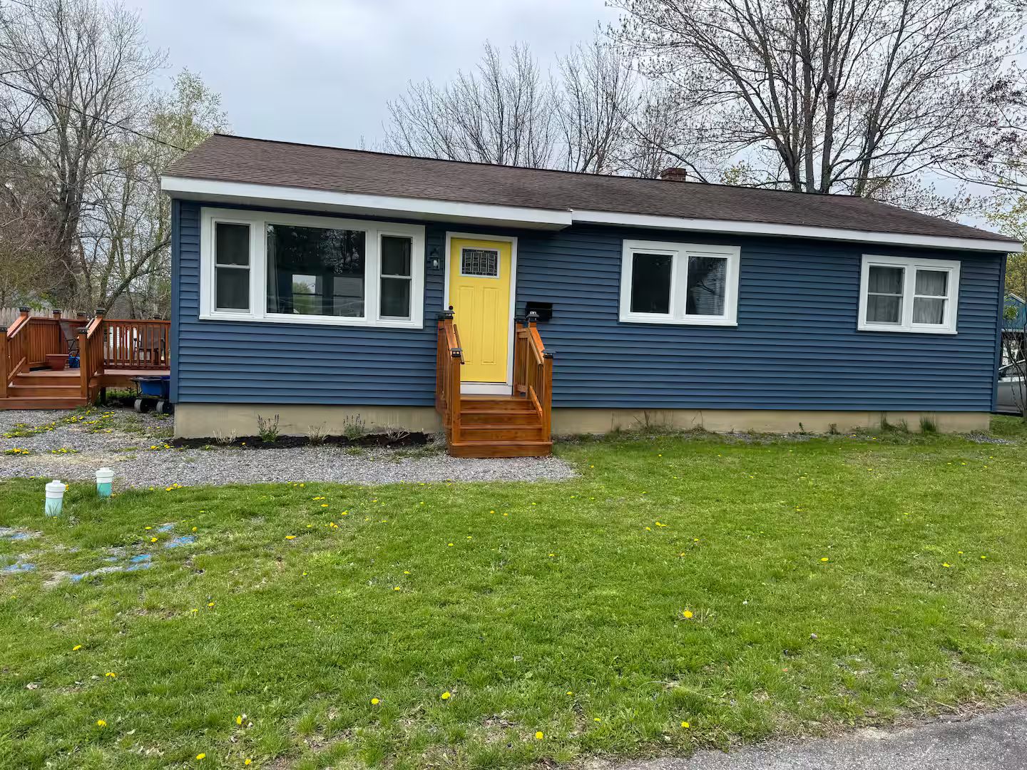A single-story house with a front porch, a yellow door, and a small front yard.