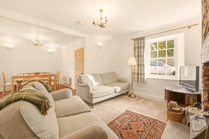 A living room with a sofa, a television, a lamp, and a patterned rug. - Hillside Cottage - North East Escapes (East Ord)