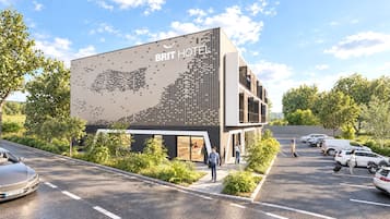 Un moderno edificio de hotel con un mural grande en la pared, un estacionamiento y huéspedes caminando.