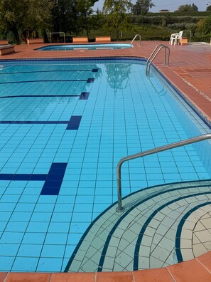 En swimmingpool med kakelbeklädd botten och ett metallräcke.