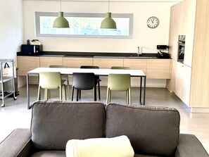 Ett modernt kök med en matplats, en soffa och en klocka på väggen.