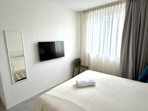 A hotel room with a bed, a flat-screen TV mounted on the wall, a chair, and a window with curtains. - Villa 'Blanka' with Shared Pool, Wi-Fi and Air Conditioning (Bardolino)