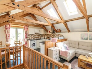 A cozy loft-style room with a kitchen, dining area, and living space. - Oak Cottage (Truro)