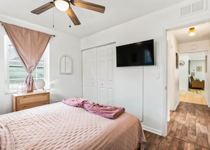 A bedroom with a bed, a ceiling fan, a TV, and a wardrobe. - Heated Pool Retreat Near Manatees & Springs (Citrus Springs)