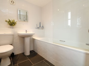 A bathroom with a toilet, pedestal sink, and a bathtub. - Hawthorn Cottage (Truro)