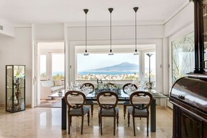 A dining area with a table set for four, a view of a cityscape and a mountain, and a large window with a view. - Villa Arpino - Four Bedroom Villa, Sleeps 8 (Vico Equense)