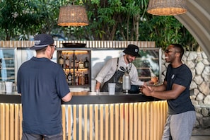 Un espace bar avec un comptoir, des bouteilles et une personne qui prépare une boisson.