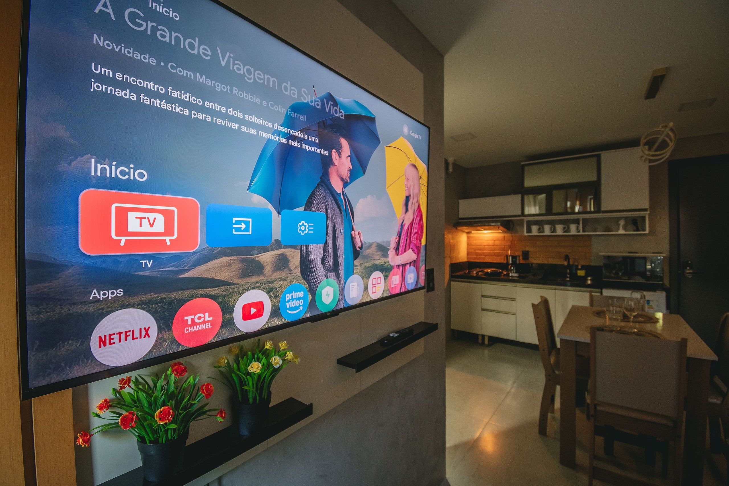 A modern living room with a large flat-screen TV mounted on the wall displaying various streaming services.