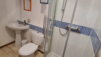 Un baño con ducha de vidrio, un lavabo e inodoro.