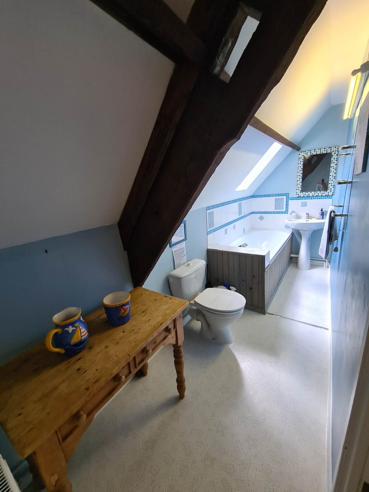 Une salle de bain avec une table en bois, des toilettes et un lavabo.