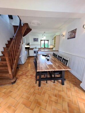 A spacious dining area with a wooden table and chairs, a kitchen in the background, and a wooden staircase. - Charming Large 4-bedroom house in Maupertuis perfect for families. Swimming Pool (Maupertuis)