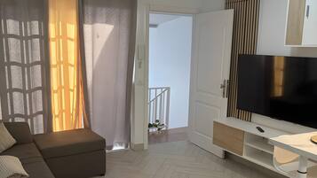 Een moderne woonkamer met een bank, een televisie en een visgraatvloer.