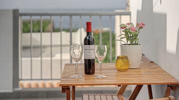 Uma garrafa de vinho, duas taças e um vaso com planta sobre uma mesa de madeira.