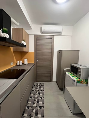 A compact kitchen with a microwave, a refrigerator, and a built-in oven. - A un Passo dalla Piazza (San Giovanni Gemini)