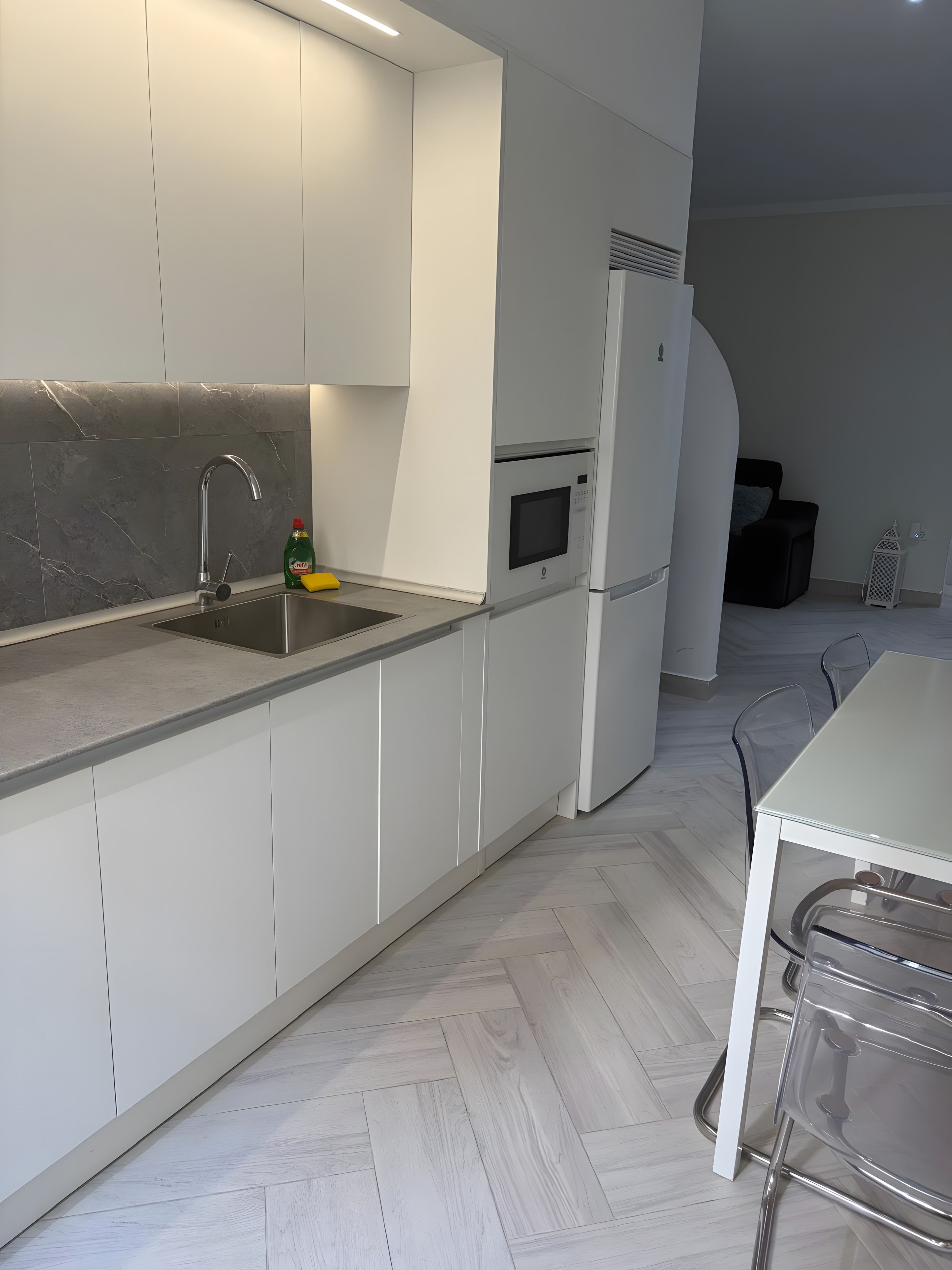 A modern kitchen with white cabinetry, a stainless steel sink, and a built-in microwave.