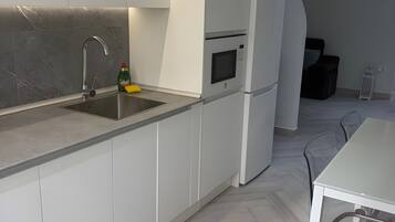 A modern kitchen with white cabinetry, a stainless steel sink, and a built-in microwave.