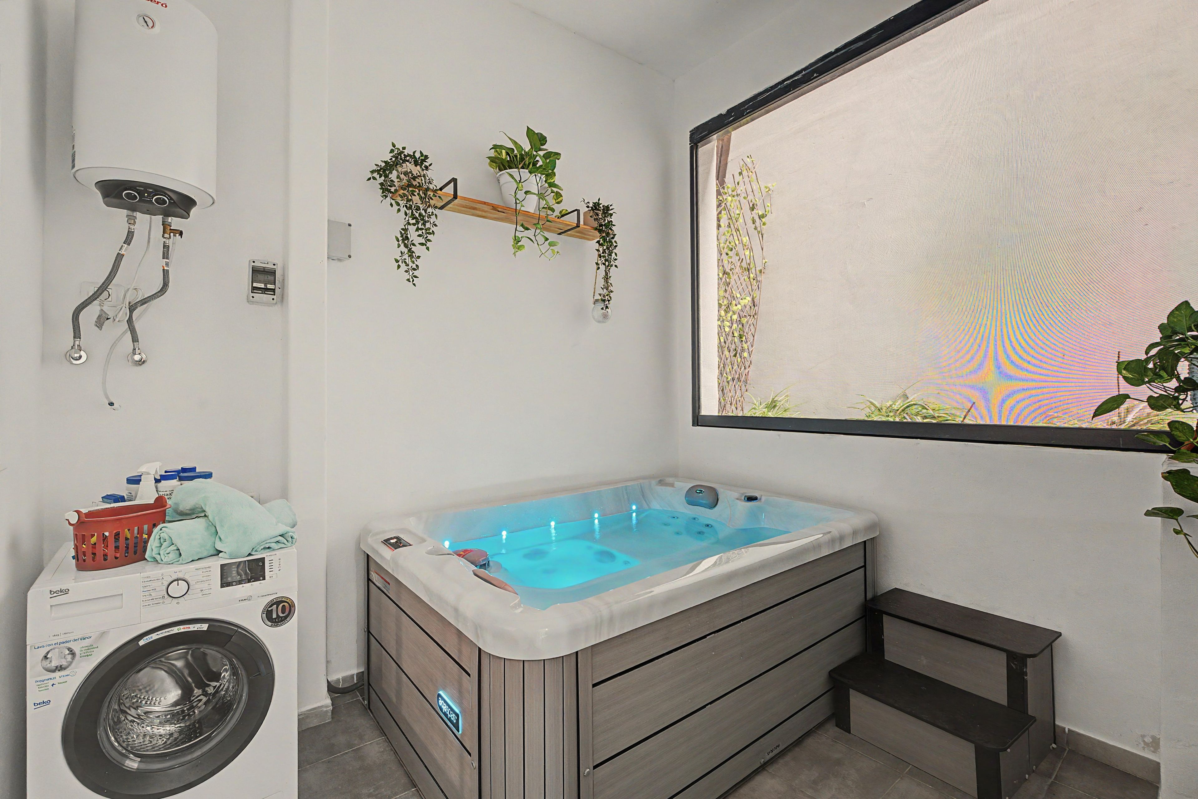 A bathroom with a washing machine, a bathtub, and a window with a view.