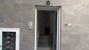 A hallway leading to a staircase with a water meter on the wall.