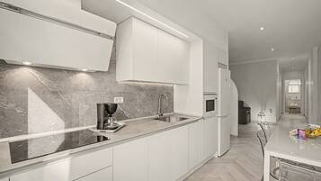 A modern kitchen with white cabinetry, a marble backsplash, and a built-in oven.