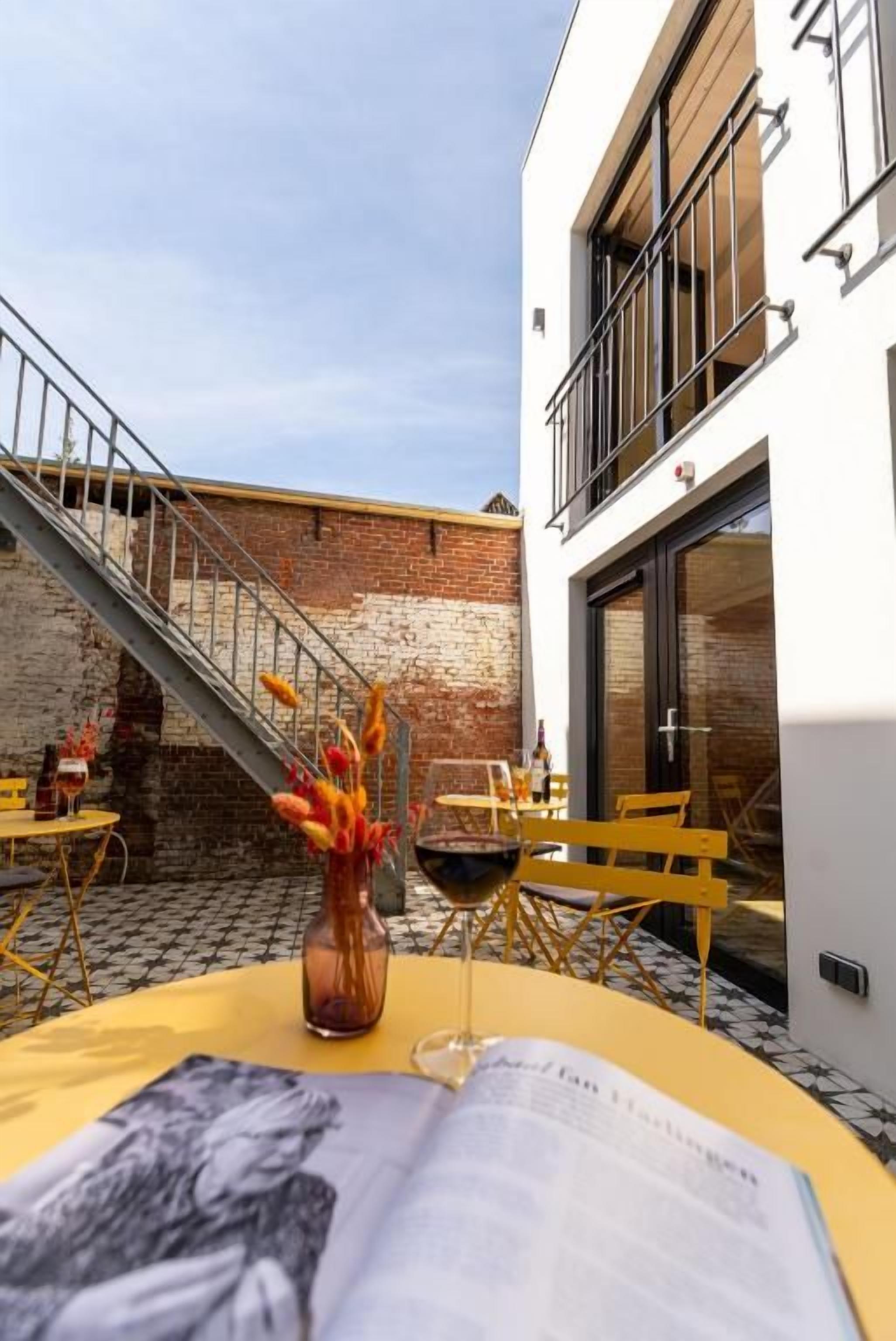 An outdoor seating area with a table, chairs, a vase with flowers, and a wine glass.