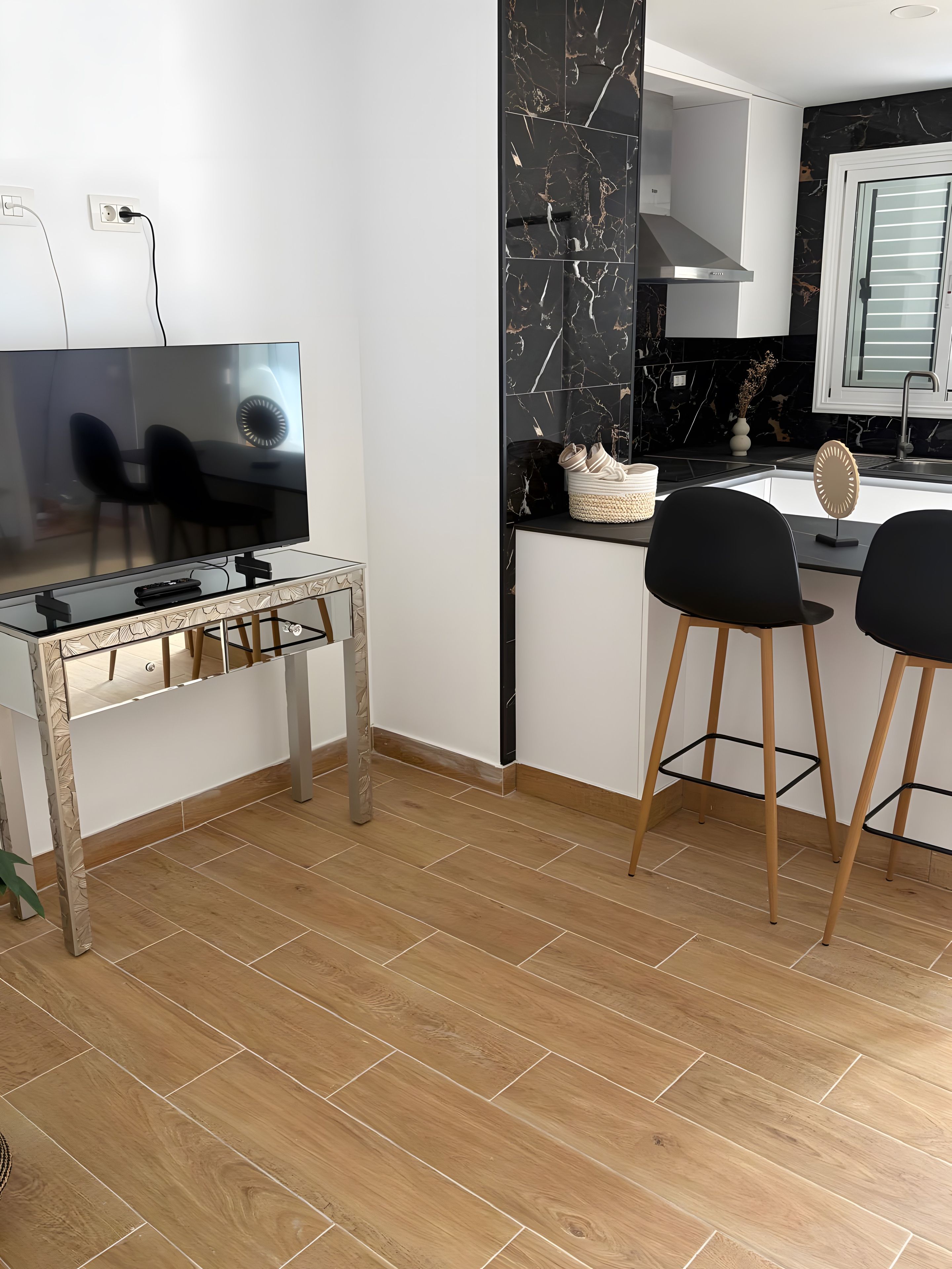 Une cuisine moderne équipée d’un téléviseur, de deux tabourets de bar et d’un pare-feu en marbre.