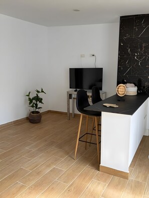 Une cuisine moderne avec un plan de travail noir, des armoires blanches et un plancher en bois.