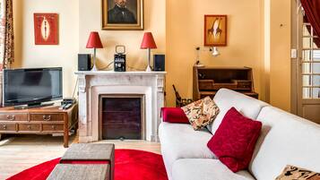 A living room with a television, fireplace, sofa, and various decorative items.