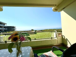 A balcony with a clear view of the sea, a table with a star-patterned tablecloth, and a vase with flowers. - Apartment "tohus" (Wyk auf Foehr)