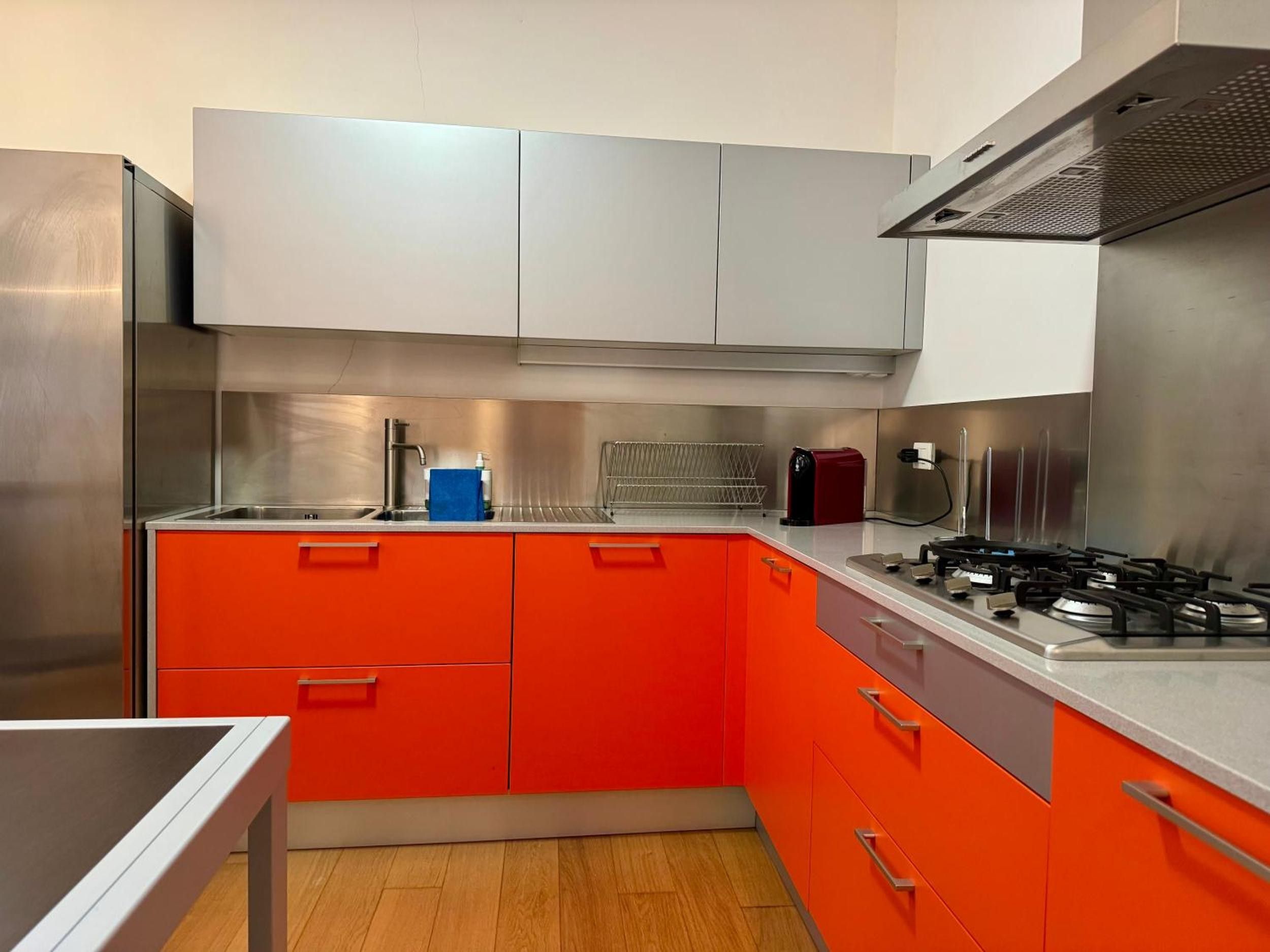 A kitchen with stainless steel appliances, a gas stove, and orange cabinets.
