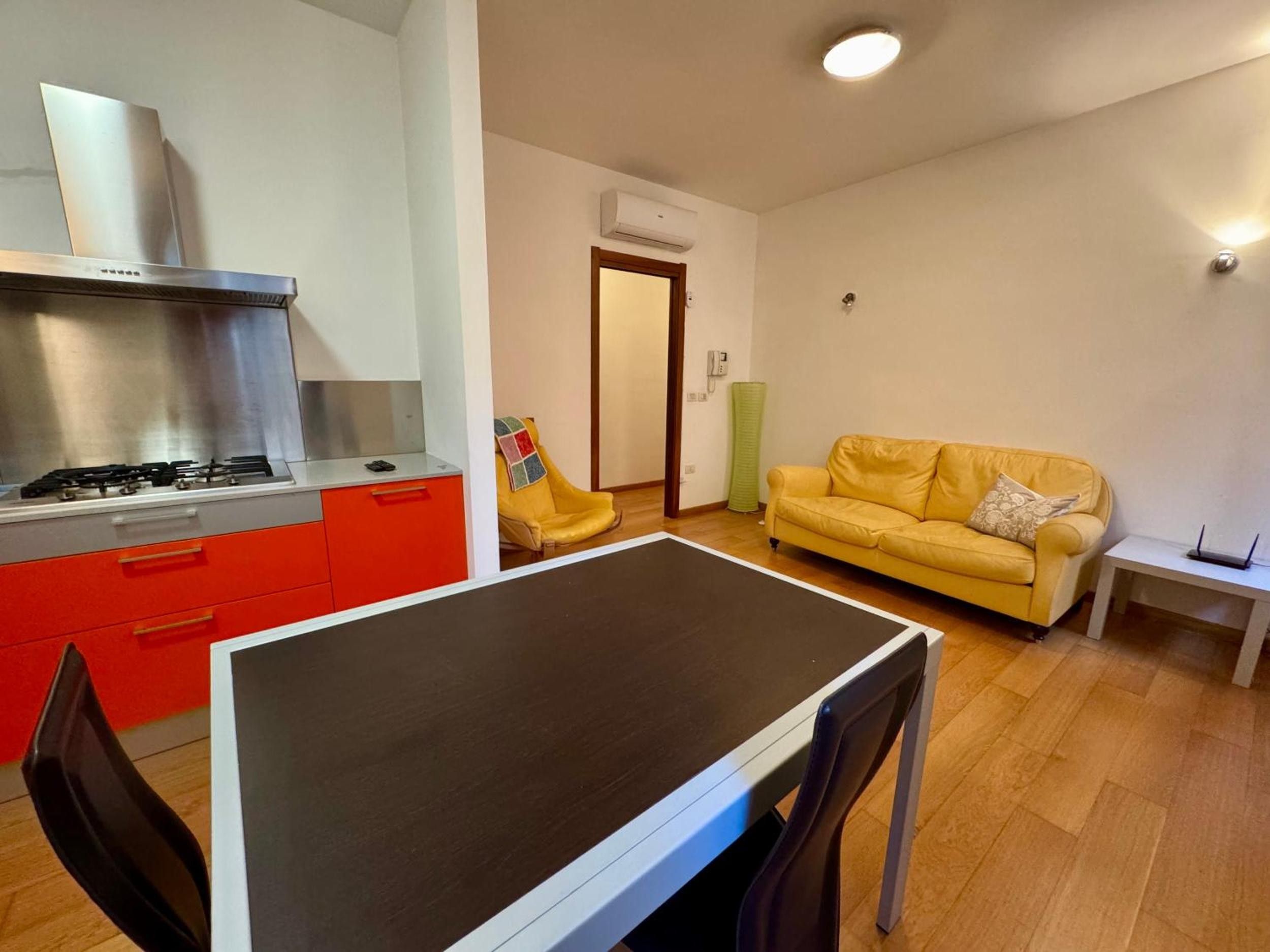 Ett kompakt bostadsutrymme med ett matbord, stolar, en soffa och ett köksområde med en spis.