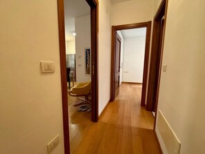A hallway with wooden flooring, a chair, and a door leading to another room. - Apartment 'Casa Emi' with Balcony, Wi-Fi and Air Conditioning (Verona)