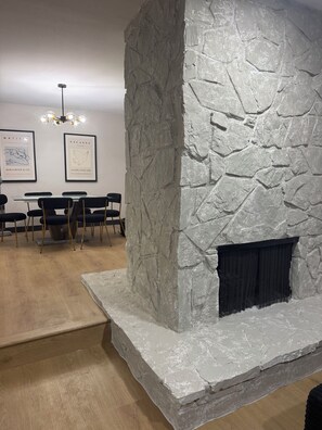 A room with a stone fireplace, a dining area with chairs and a table, and framed artwork on the wall. - Villa Belle, a stylish retreat just 10 minutes from the Strip and the airport (Las Vegas)