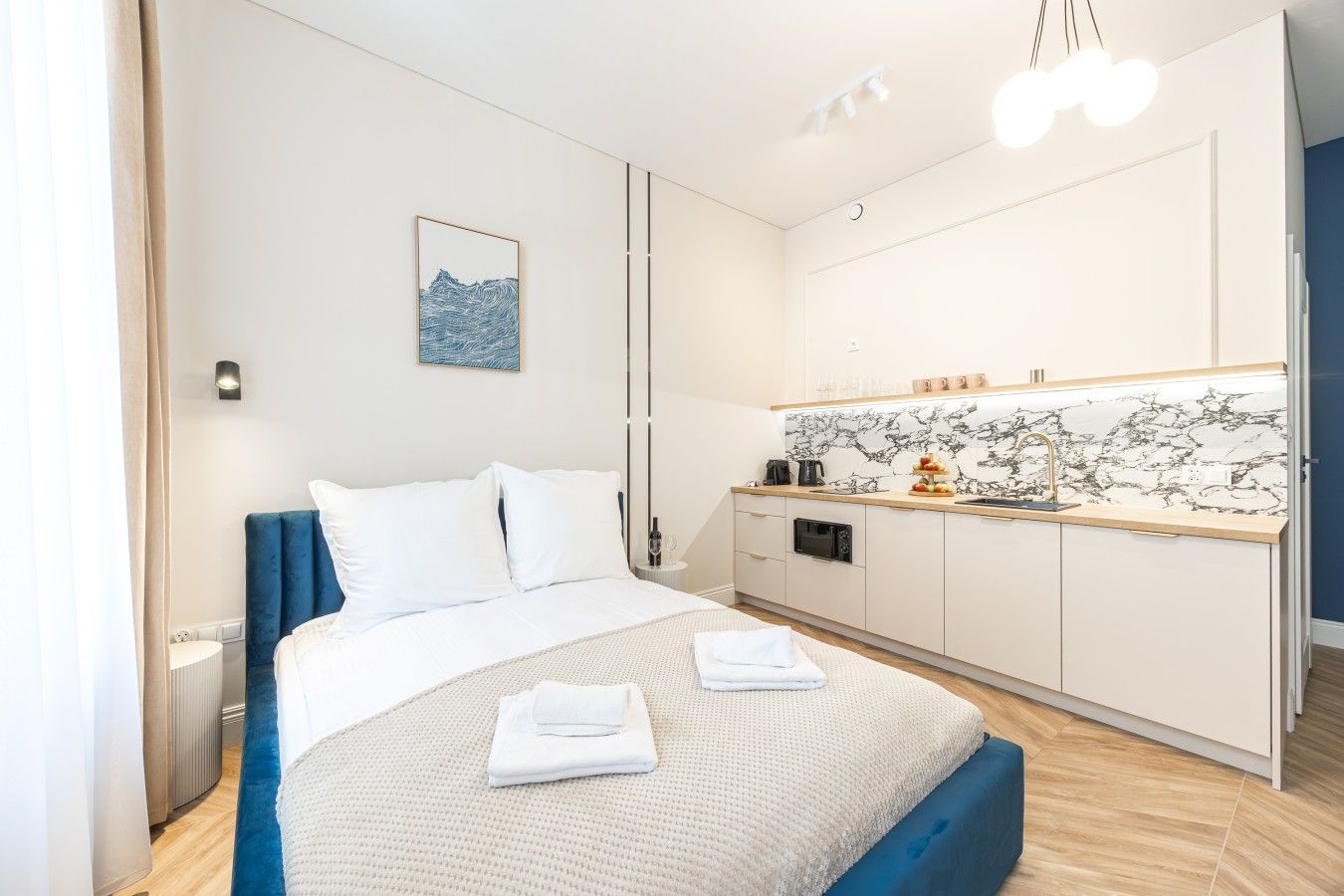 A hotel room with a bed, a small kitchenette, and a bathroom.