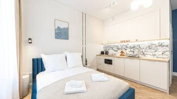 A hotel room with a bed, a small kitchenette, and a bathroom.