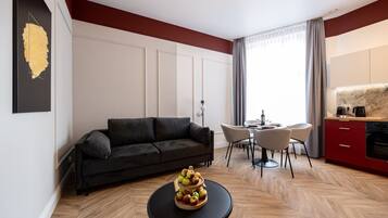 A modern living room with a sofa, dining table, and kitchen area.