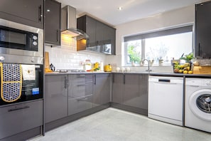 Una cocina moderna con electrodomésticos de acero inoxidable, lavavajillas y un ventanal que proporciona luz natural.