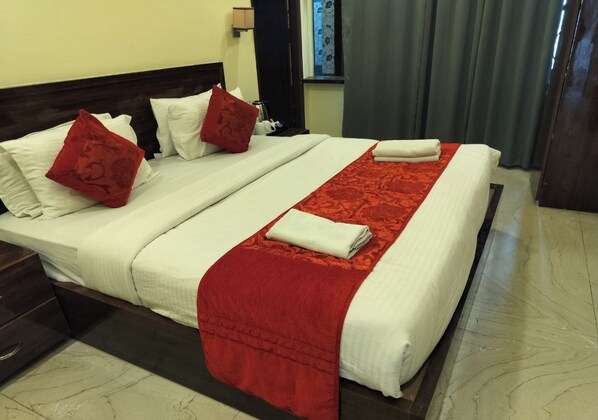 Una cama bien hecha con sábanas blancas, almohadas rojas y una manta roja.