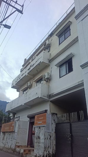 A multi-story building with a signboard for 'Mrityunjay Yogpeeth' and a gated entrance. - Ganesha Inn A River View Stay  (Rishikesh)