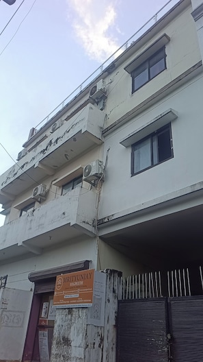 Un edificio de varios pisos con unidades de aire acondicionado, un letrero para un centro de yoga y una entrada con puerta de reja.