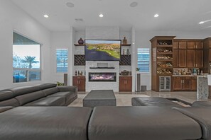 A modern living room with a large flat-screen TV, a fireplace, and a wine rack. - Lake Las Vegas Home (Henderson)